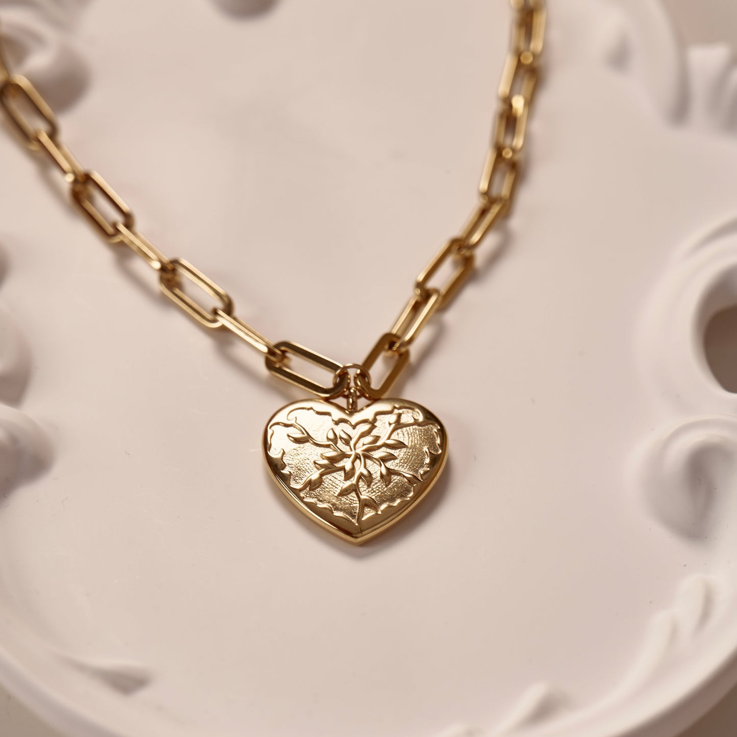 Collier doré en acier inoxydable, avec pendentif en forme de cœur, avec un design unique rappelant des feuilles d'olivier. Chaîne à grosse maille réglable. Bijou résistant, élégant et symbolique.