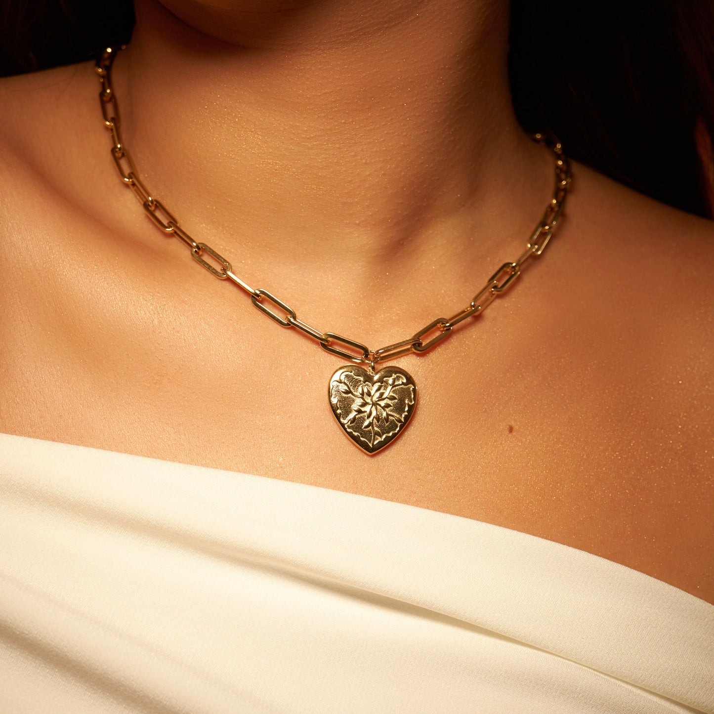 Collier doré en acier inoxydable, avec pendentif en forme de cœur, avec un design unique rappelant des feuilles d'olivier. Chaîne à grosse maille réglable. Bijou résistant, élégant et symbolique.